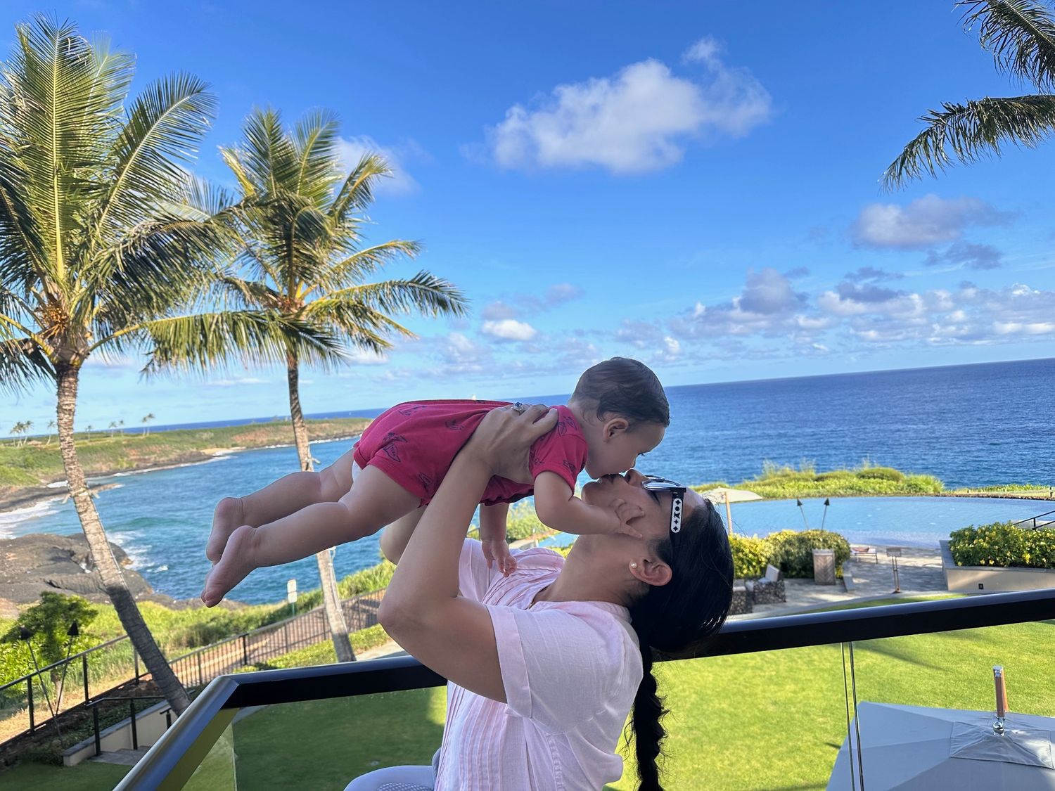 Claudia holding her child by the ocean in Hawaiʻi